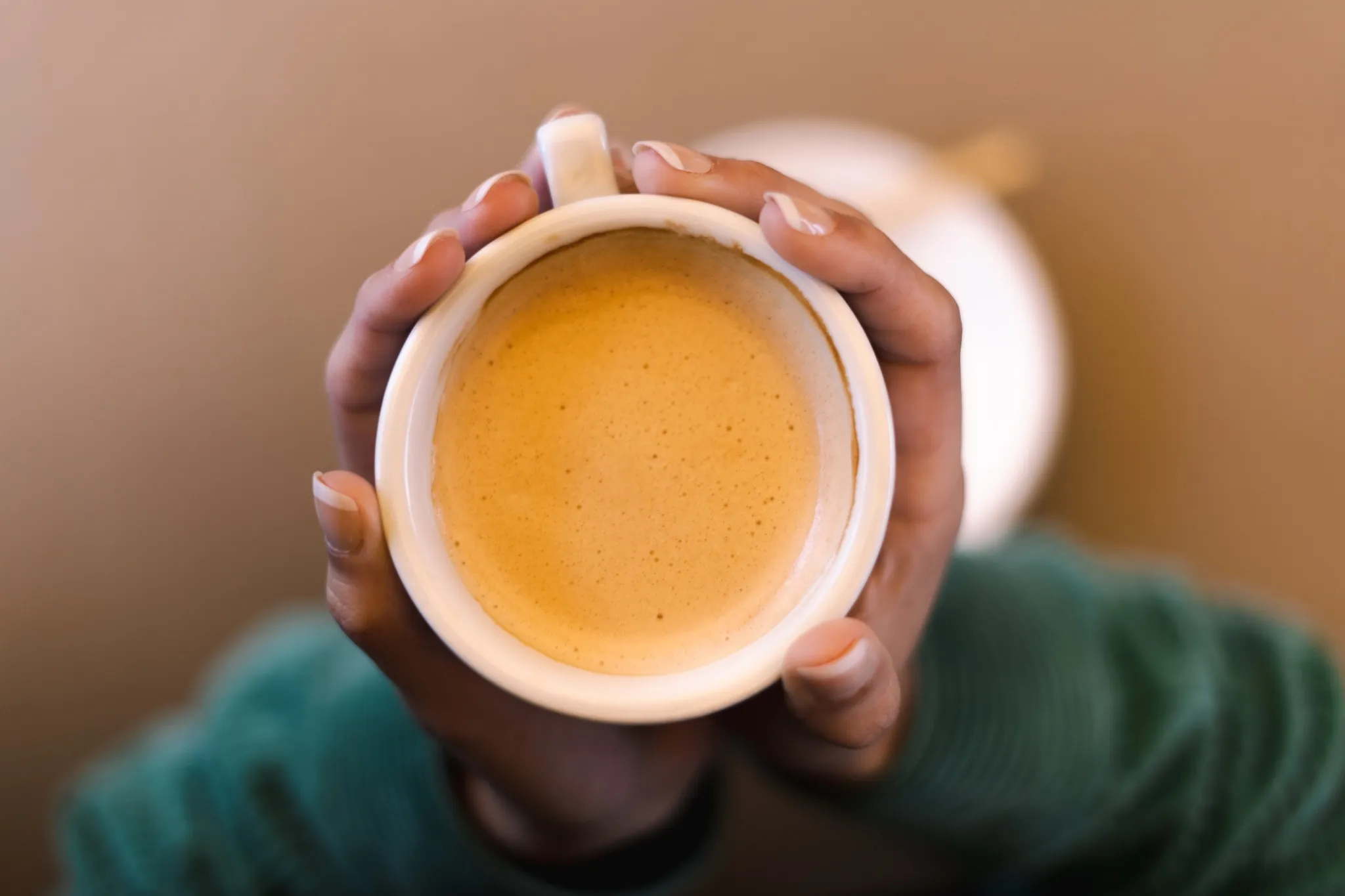 Café con leche en taza con el logo de El Café de Manuela