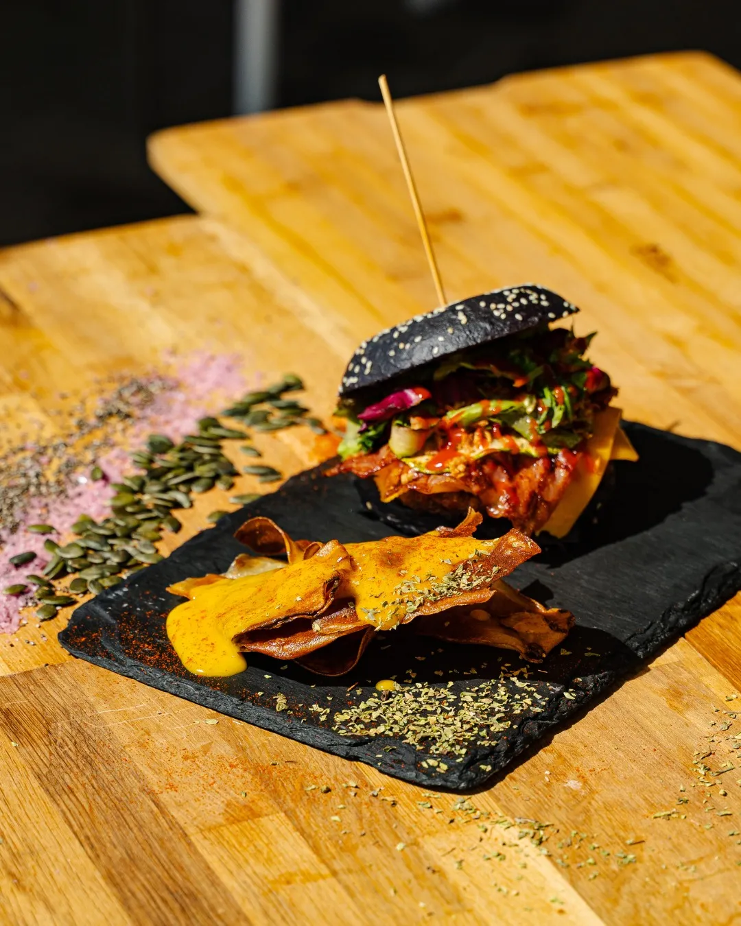 Hamburguesa en pan negro con queso y bacon