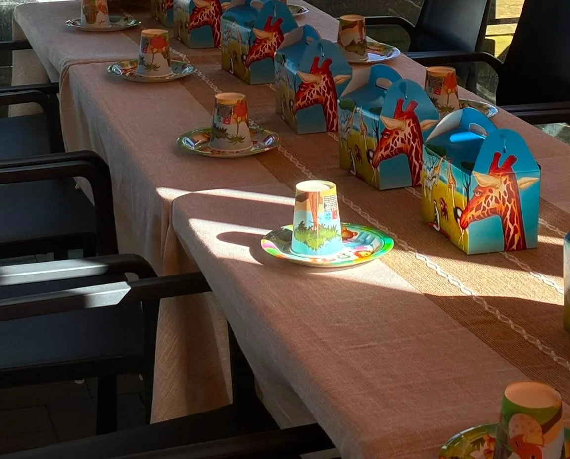 Mesa larga puesta para un cumpleaños infantil, con cajitas de sorpresas