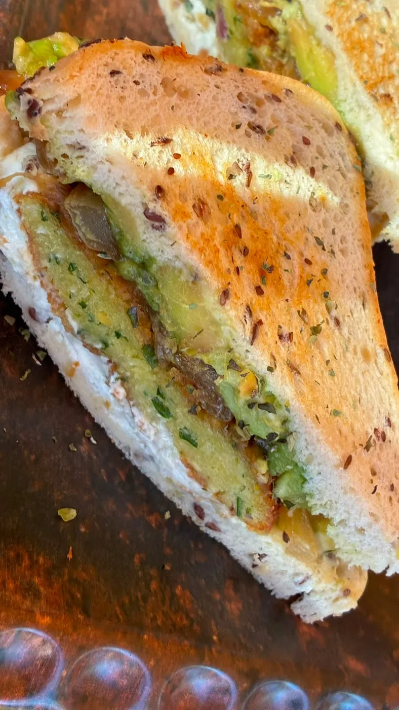 Sándwich vegetariano en pan de semillas, con aguacate y cebolla caramelizada
